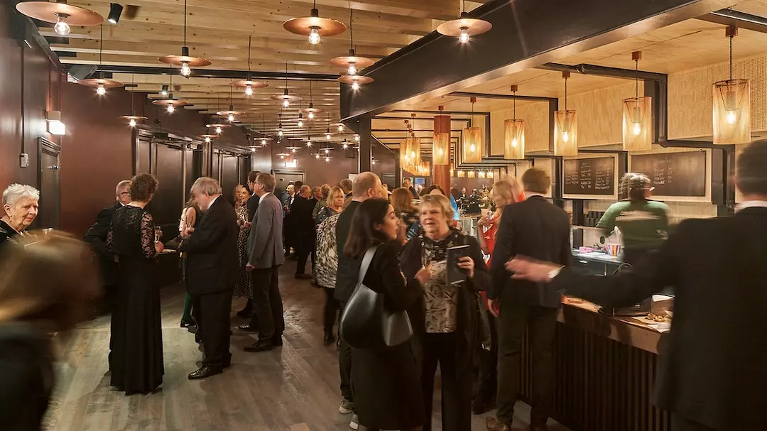 theater-goers gather around a lively bar
