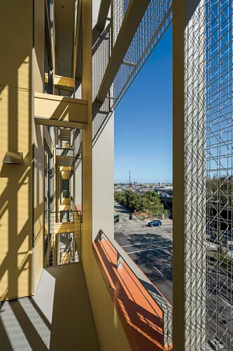 The design, with cement-board panels and brick cladding, includes open outdoor spaces that puncture the exterior wall plane.