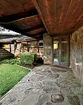 From there a covered path edges an open courtyard to the front door, angled between the living room and a hallway for the bedroom wing.