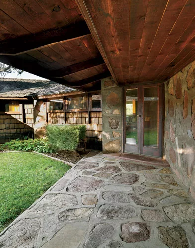 From there a covered path edges an open courtyard to the front door, angled between the living room and a hallway for the bedroom wing.