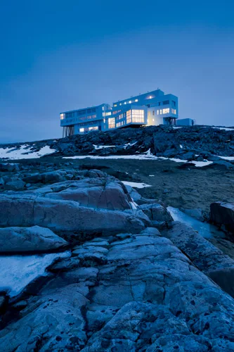 The steel-frame, concrete-slab structure is heated by wood-burning boilers, taking advantage of a local resource. Solar panels on the roof of the inn and an adjacent services building supp