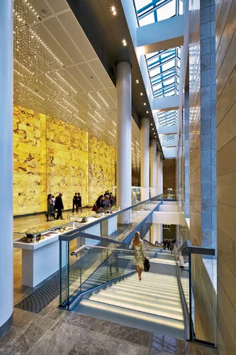 Daylight filters into the lobby through skylights and windows along the building's north side. The onyx wall envelops the auditorium and backs onto the lobby, illuminated by rows of glittering Sw