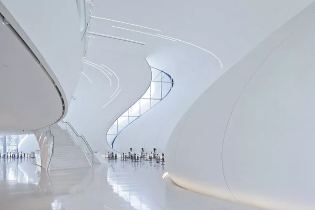 The unbridled swooping forms and blinding brightness of the glass-fiber-reinforced plastic exterior carry through to the building’s interiors, where floors merge into walls, stairs, and 