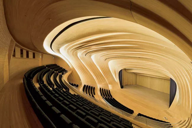 Backlighting emphasizes the dynamism of the 1,000-seat auditorium’s pleated oak paneling and underscores the contrast between the materials here and those used in the rest of the building.