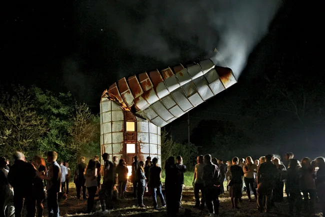 During the weekend celebration, photographer Timothy Hursley hosted a bonfire party at the silo he owns in a remote pasture. The deformed structure was reportedly the victim of a tornado.