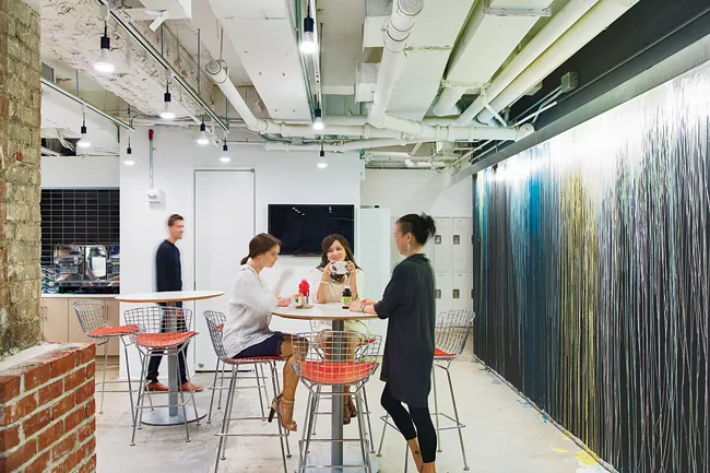The café features exposed ceilings and an end wall painted by the staff to look like an abstract painting.