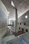 Floating columns distribute the weight of the roof to the enclosed spaces via transfer beams, one of which incorporates a small terrace on which musicians can have a break from the adjacent rehearsal 