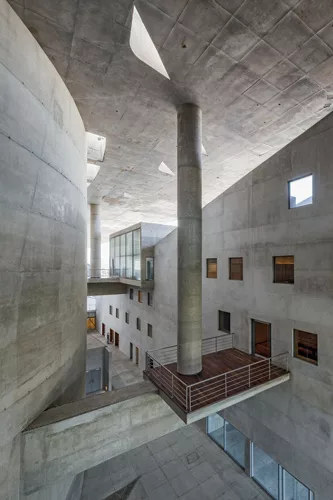 Floating columns distribute the weight of the roof to the enclosed spaces via transfer beams, one of which incorporates a small terrace on which musicians can have a break from the adjacent rehearsal