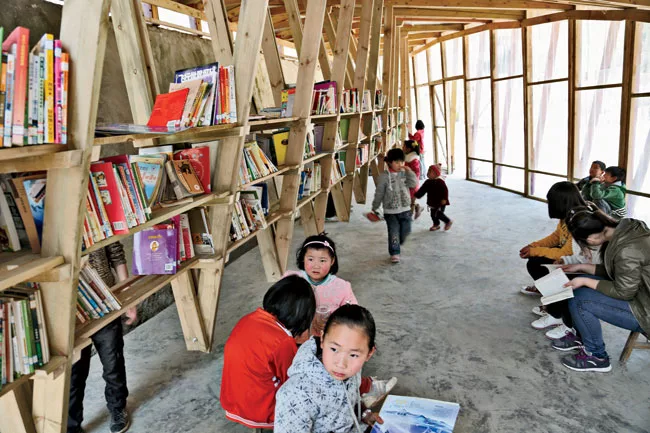 A system of 17 trusses assembled on-site supports the double-curved roof; V-shaped extensions of the trusses support bookshelves that run the length of the space.