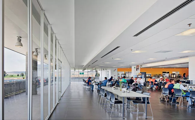 Amenities, like the sun-filled cafeteria, provide comfortable employee downtime and a place for management to share ideas with the production team.