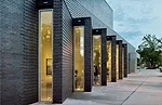 Windows set into successive angles make a sawtooth-shaped brick wall enliven the walk to the Crystal Bridges Museum of Art.