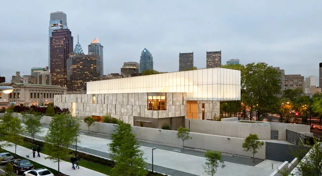 The actual entrance to the Barnes occurs at the east end of the north facade, not on the Parkway. A landscaped court separates the structure from a parking lot (foreground) near the loading dock at