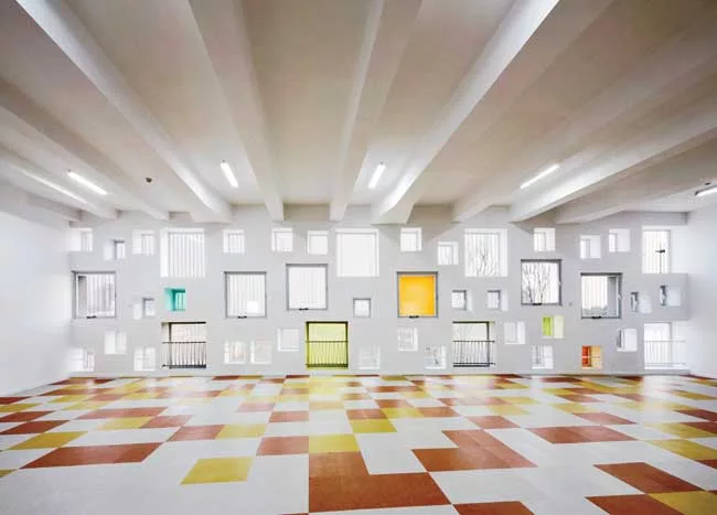 In the kindergarten, two parallel structures play in opposition to each other. A formidable concrete block encloses the circulation ramps for the school, while a punctured block with perforated alumin