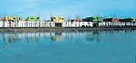 Fifteen classrooms, dining rooms, and courtyard play spaces nestle together in a long white band that follows the curve of an adjacent river. Fifteen corresponding nap rooms painted in bright colors s