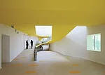 In the kindergarten, two parallel structures play in opposition to each other. A formidable concrete block encloses the circulation ramps for the school, while a punctured block with perforated alumin