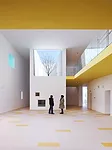 In the kindergarten, two parallel structures play in opposition to each other. A formidable concrete block encloses the circulation ramps for the school, while a punctured block with perforated alumin
