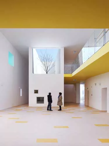 In the kindergarten, two parallel structures play in opposition to each other. A formidable concrete block encloses the circulation ramps for the school, while a punctured block with perforated alumin