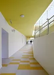 In the kindergarten, two parallel structures play in opposition to each other. A formidable concrete block encloses the circulation ramps for the school, while a punctured block with perforated alumin