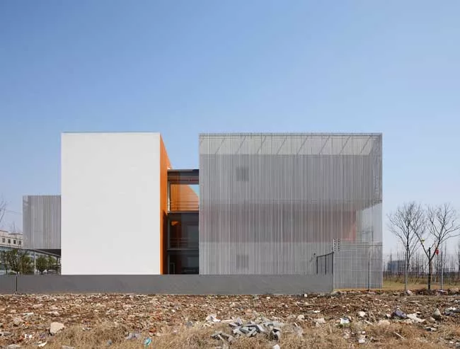 Surrounded by roads and vacant lots on three sides, the site for this building has just one notable feature: A river that runs along its north side. On its short sides, the building appears as a pair 