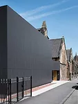 Asked to renovate an unremarkable 1970s annex to a church in Glasgow, the architects wrapped the building in black cement boards to provide a clear, flat contrast to the stone architecture next door. 