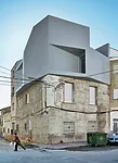 The client added a one-bedroom penthouse to the modest building where his mother and sister live. The architects oriented windows at oblique angles to the streets for views and protection from direct 