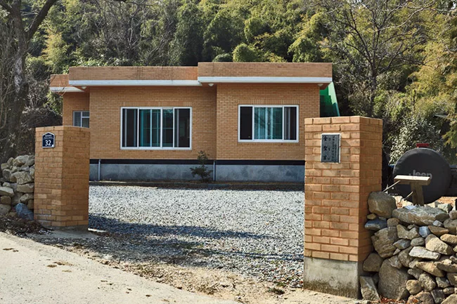 The owner of a Seoul design company owned an ugly brick house in the mountains in Namhae county (left), where he liked to escape. He decided to make it more welcoming, so he hired JOHO to remake the b