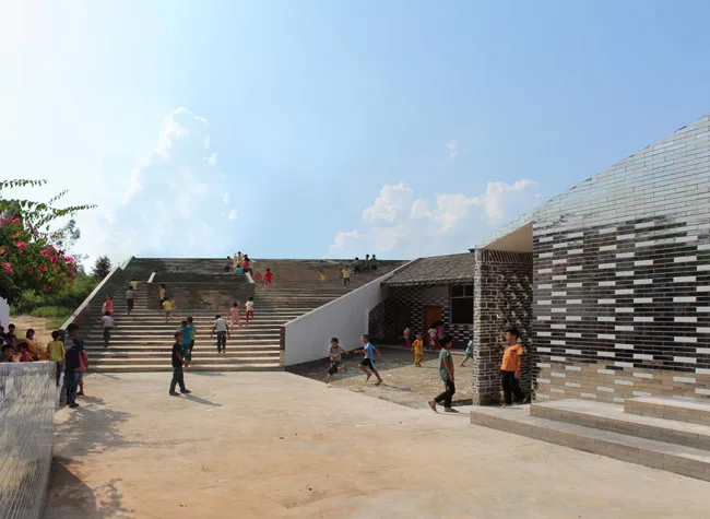 With this six-classroom addition to a primary school in Jiangxi Province, RUF produced a U-shaped structure with a courtyard open on one side. A continuous roof begins as a series of steps, providing 