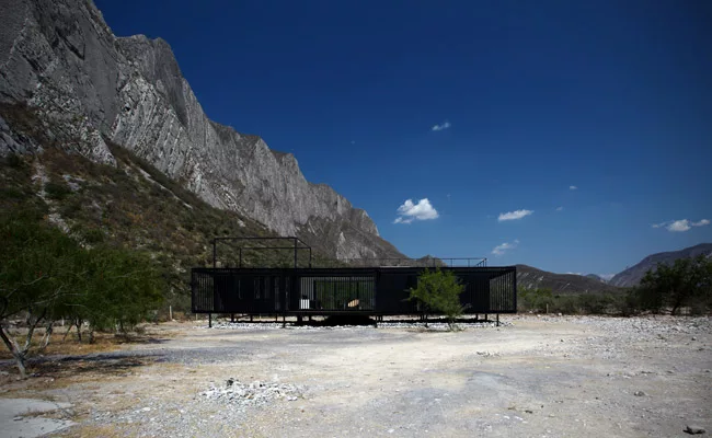 The diminutive house floats over the rugged terrain, enabling water runoff to pass below.