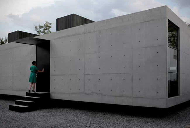 This private residence wears its rough material palette on its sleeve. Inside and out, the reinforced concrete walls and floors of the low box are left exposed and unadorned, punctuated by simple deta