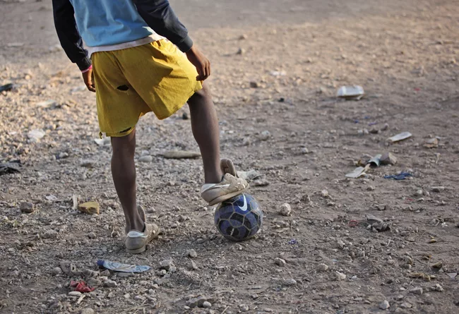 A boy readies himself for the kick-off of an impromptu soccer game. <em>January 2012</em>.