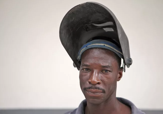A welder pauses for a moment while his co-workers rearrange his materials. <em>January 2012</em>.