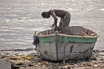 A fisherman makes repairs to a small handmade boat in Cit' Soleil, a slum in Port-au-Prince. <em>January 2012</em>.