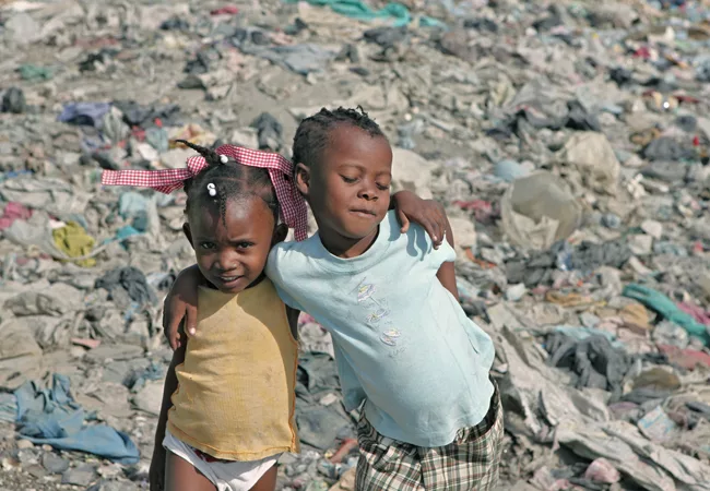 Two girls pose for the camera while playing in a landfill in Cit' Soleil. <em>January 2012</em>.