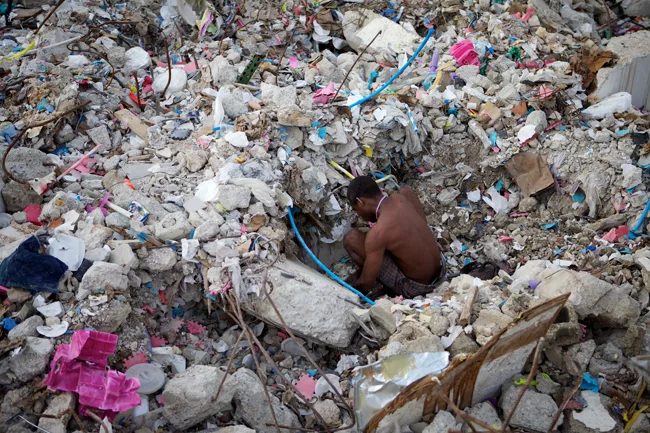 A man digs through the rubble of a collapsed four-story market in Port-au-Prince. <em>April 2010</em>.