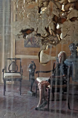 In a water-damaged mirror, a reflection of Madame Viviane Gauthier, a renowned 93-year-old dance instructor who resides in a historic gingerbread house in Port-au-Prince. <em>January 2012</em>.