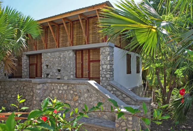 The building is partly shaded by palm trees.