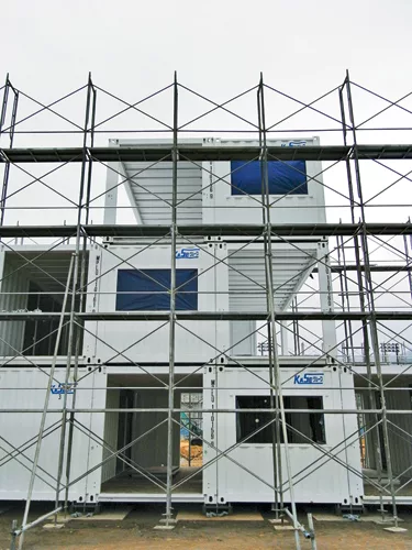 Quick to construct (and deconstruct), the buildings consist of shipping containers stacked and secured by a steel frame. For insulation and seismic resistance, they are arranged in a checkerboard patt