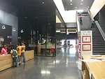 Next to the front desk, glass-walled offices bring transparency to administrative functions. The children's reading room is visible at the far end of the ground floor and a central stair leads to the 