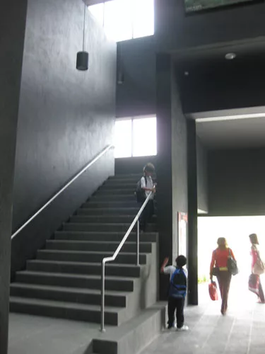 The entry atrium opens up off of a pedestrian path and car drop-off.