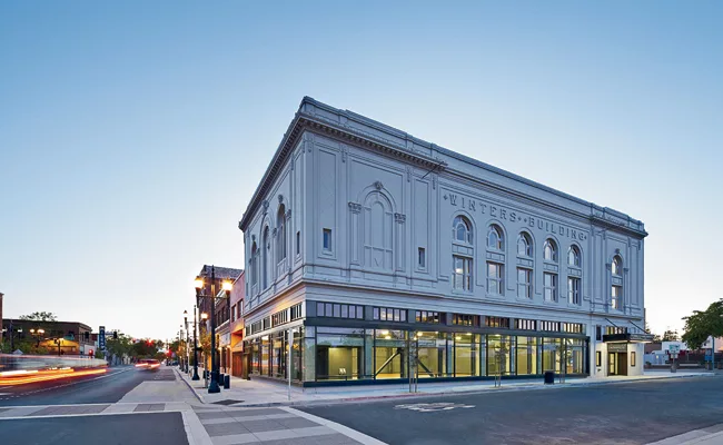 The Winters Building, circa 1924, sits on a corner lot. The design team removed years of grime, stucco, and other buildup on the facade, in addition to demolishing the old interiors. At night, large w