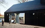Thick doors open to reveal mirrors on their backsides, composed of polished stainless steel. The doors provide access to the inside of the building, where bathrooms, a playroom, a kitchen, areas for e