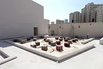 The conceit is difficult to read without a bird’s eye view of the space, and cubic ottomans—geometric takes on Orientalist kitsch—and carpets used for seating trivialize the design, 