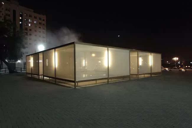 Studio Mumbai’s second pavilion, set up near the quay along Sharjah creek, encloses a fountain spraying mist inside a screened-in seating area.