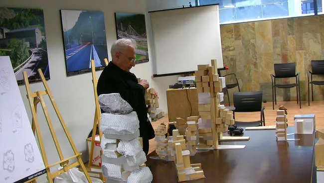 Still from <em>The Competition</em>: Frank Gehry looks over models before his presentation.
