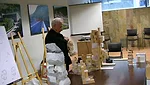 Still from <em>The Competition</em>: Frank Gehry looks over models before his presentation.