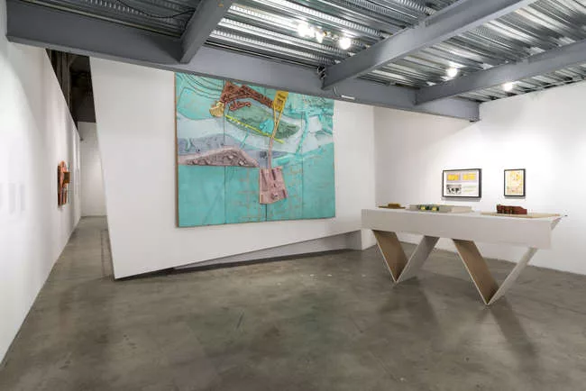 The installation includes an original 1976 model of <em>The RIver and the City</em>, a scheme by Studio Works (Craig Hodgetts and Robert Mangurian) for Minneapolis' Nicollet Island. The diagonal table