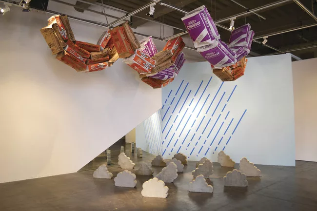 Playing with the conventions of what goes up and what comes down, Design, Bitches created an environment where concrete sacks float, blue painter’s tape showers the ground, and clouds fall like