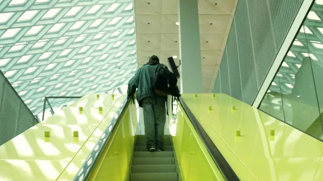<p>Film Still from <em>REM</em>:</p><p>A homeless man takes refuge in OMA’s Seattle Public Library</p>