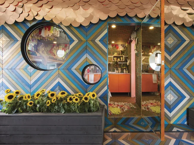 SCAD alumna and featured artist Trish Andersen sitting on the fold-up hammock bed, which accommodates the desk underneath, in one of the SCADpads. The fold-up hammock bed was designed and constructed