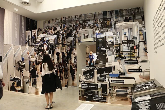 Large photo cutouts of airport security checkpoints in the Door gallery.